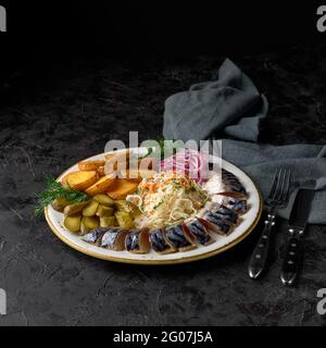 Maquereau légèrement salé avec concombres marinés, choucroute, oignons marinés et pommes de terre frites. Hors-d'œuvre photo pour le menu, cuisine russe traditionnelle. Banque D'Images