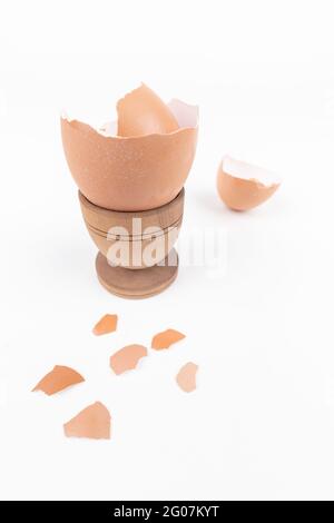 Coquille d'œuf cassée dans le vieux bois par exemple stand et dispersé sur la surface blanche. Minimalisme. Concept de produit animal. Petit déjeuner simple. Problème de durabilité Banque D'Images