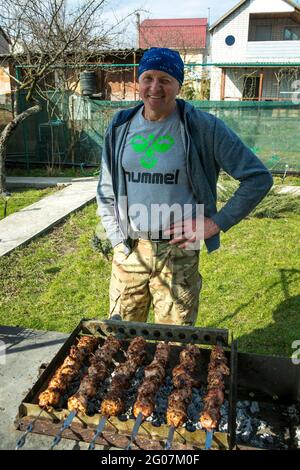 Pique-nique dans la nature. Un homme grille des kebabs marinés. Gros plan photo de kebabs de cuisine caucasienne dans le jardin du cottage. Banque D'Images