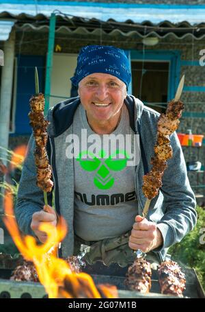 Pique-nique dans la nature. Un homme grille des kebabs marinés. Gros plan photo de kebabs de cuisine caucasienne dans le jardin du cottage. Banque D'Images