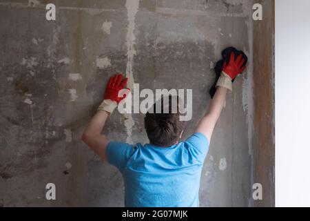 Homme caucasien lavant les murs de la poussière à l'aide d'un vieux chiffon Banque D'Images