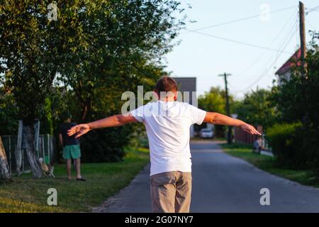 Redéfinit le jeune garçon heureux jouant sur le skateboard dans la rue. Il a mis les bras sur les côtés. Les enfants de race blanche à la planche de Penny, à la pratique du skateboard. C Banque D'Images