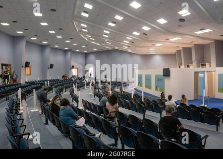 Les gens bavarder en attendant l'anamnèse au Centre des congrès. Selon le programme “îles sans Covid” pour l’été, la population de Lipari, la plus importante des îles éoliennes de Sicile, a reçu le vaccin anti COVID-19 au Palais des Congrès. Le programme a été exécuté par une équipe de la région sicilienne, sous la direction du Commissaire spécial pour l’urgence Covid-19 de la zone métropolitaine de Messine (Ufficio Commissario ad Acta per l’Emergenza Covid-19 per l’Area Metropolitana di Messina) et avec l’aide de la Marine italienne. Banque D'Images