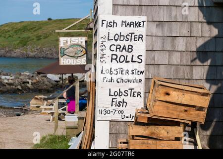 Un panneau écrit peint à la main pour le marché du poisson avec les offrandes de la journée - homard, rouleau de crabe, poisson-chowder. Sur l'île Monhegan dans le Maine. Banque D'Images