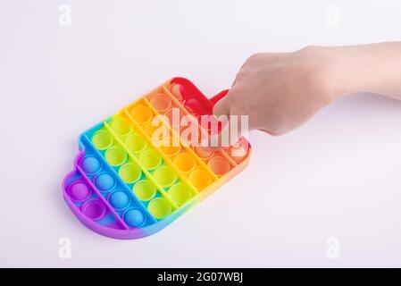 Les enfants jouent à la main avec le jouet de violon coloré arc-en-ciel pop il isolé sur le blanc. Banque D'Images