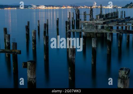 Old Pier pidings dans l'eau calme la nuit avec la ville en arrière-plan Banque D'Images