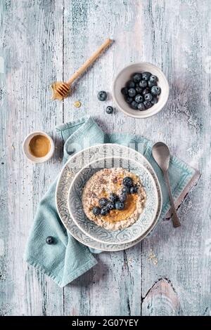 Au-dessus de délicieux porridge d'avoine frais de nuit avec des bleuets et de la crème sur une serviette de cuisine sur une table lumineuse en bois Banque D'Images