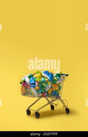 Chariot de divers emballages en plastique coloré sur fond jaune Banque D'Images