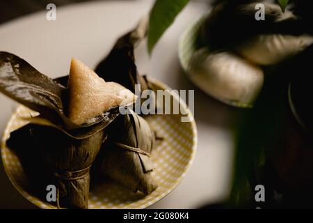 Boulettes de riz ouvertes et couvertes de feuilles de bambou placées sur mignon plaque vérifiée Banque D'Images