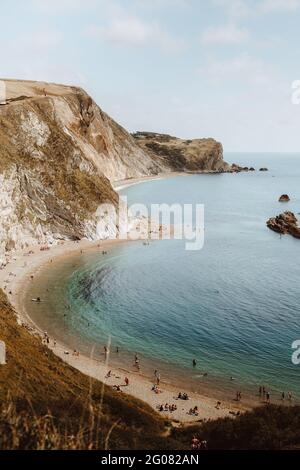 Depuis le haut paysage idyllique de mer avec des rochers appelés Durdle Door et les gens se détendent sur la mer le jour de l'été Banque D'Images