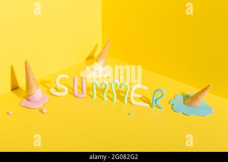 De dessus de mackup des cornets de gaufres avec de la glace colorée fondue Crème placée sur fond jaune avec inscription Summer Banque D'Images