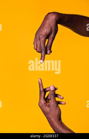 Les mains opposées d'un homme afro-américain qui se pointe l'un vers l'autre index isolé sur fond jaune Banque D'Images