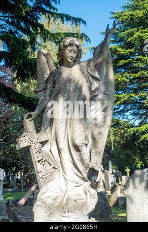 Une sculpture d'une figure angélique, une dame tenant une croix fait partie d'une pierre angulaire dans le cimetière Hanwell à Londres, au Royaume-Uni. Banque D'Images