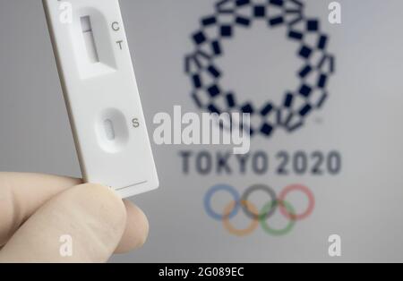 Test PCR négatif à l'avant et logo Tokyo 2020 flou sur fond flou. Concept pour les Jeux Olympiques de Tokyo COVID en 2021. Stafford, United King Banque D'Images