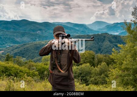 Hunter visant un tir avec un fusil de sniper haut dans la région de montagne Banque D'Images