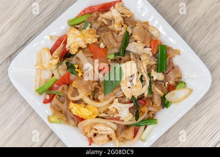 Vue de dessus de grosses nouilles sautées faites frire avec le basilic sur la pile de légumes pour cette délicieuse saveur thaï épicée. Banque D'Images