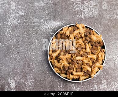 Pâtes en sauce crémeuse avec foie de poulet sur une assiette ronde sur fond sombre. Vue de dessus, plan d'appartement Banque D'Images