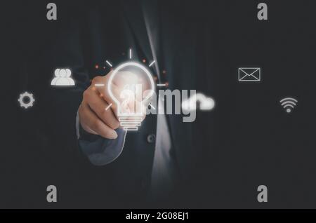 Homme d'affaires touchant l'ampoule icône d'écran médias sociaux et réseaux. Business concept Technology Process System. Banque D'Images