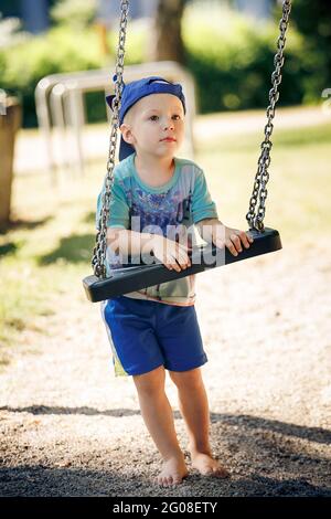 Portrait d'un petit garçon jouant avec balançoire au parc Banque D'Images