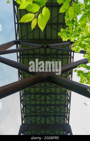 Nouveau pont de gorge de rivière vu directement en dessous montrant la structure de support. Avec des feuilles de printemps vertes au premier plan Banque D'Images