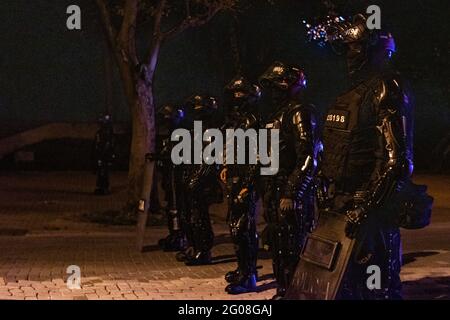 Medellin, Colombie, le 31 mai 2021. La police anti-émeute de Colombie ESMAD se tient en ligne comme un groupe de manifestants à capuchon des affrontements avec la police anti-émeute de Colombie (ESMAD) à Medellin, Colombie lors des manifestations anti-gouvernementales en cours contre la réforme fiscale et sanitaire du président Ivan Duque et les brutalités et troubles de la police qui ont fait au moins 70 morts au cours du mois dernier, à Medellin, en Colombie, le 31 mai 2021. Banque D'Images