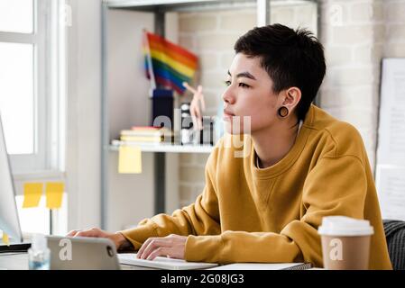 Jeune femme de tomboy asiatique en tenue décontractée travaillant de la maison dans le salon Banque D'Images