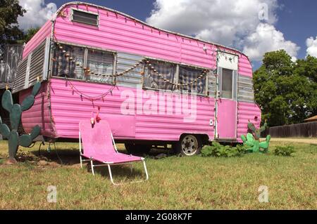 Remorque de voyage rose avec chaise et cactus avec ciel bleu et nuages Banque D'Images