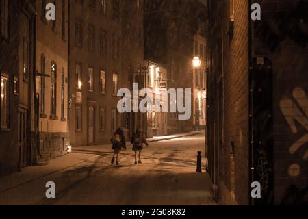 Les filles descendent dans une rue au cœur de la vieille ville de Québec, au Canada, lors d'une nuit d'hiver enneigée Banque D'Images