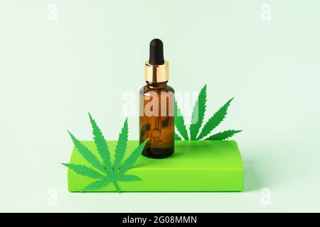 Extrait d'huile de cannabis en bouteille de gouttelettes sur fond vert. Huile de CBD de marijuana médicale. Médecine alternative, cosmétiques naturels à base de plantes. Banque D'Images