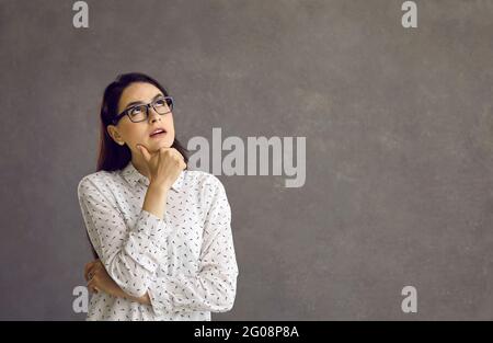 Jeune femme caucasienne pensant se tenir isolée sur fond gris studio Banque D'Images