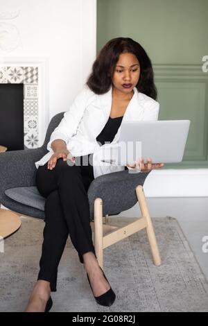 Entrepreneur féminin. Une femme d'affaires afro-américaine joyeuse travaillant sur un ordinateur portable dans un bureau moderne. Banque D'Images