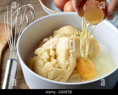 processus de fabrication de la pâte de crème anglaise pour les eclaloires et les feuilletés à la crème, l'oeuf est en train d'ajouter Banque D'Images