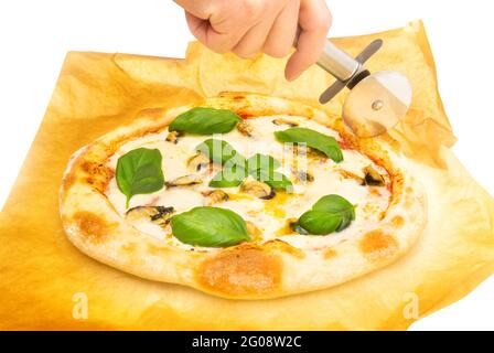 Couper une pizza de fruits de mer maison sur un papier parchemin Banque D'Images
