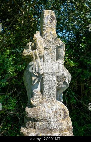 Une statue fortement endommagée de deux figures, une Christ une croix sur une colonne de pierre près de la route près de Bruisyard Hall, Suffolk, Royaume-Uni Banque D'Images