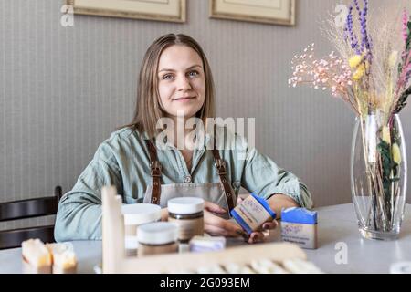 Une machine à savon pour femme prépare et emballe du savon fait main fraîchement préparé et des cosmétiques pour le soin du corps. Processus d'assemblage des commandes. Spa à la maison. Petit bus Banque D'Images