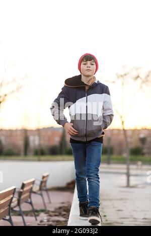 Élégant jeune garçon vêtu d'une veste en denim et d'un chapeau en tricot sur fond de ville en gros plan Banque D'Images