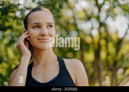 La prise de vue en extérieur de sportswoman permet d'écouter votre liste de lecture préférée dans les écouteurs, tandis que l'entraînement au parc est doté d'un sourire doux concentré sur les poses de distance trop floues Banque D'Images