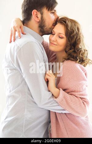 Vue latérale du couple amoureux du contenu qui s'embrasse doucement sur le blanc arrière-plan à la maison Banque D'Images