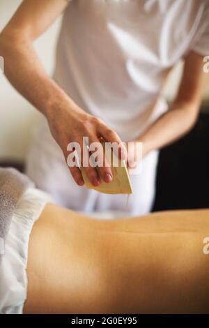 Une masseuse sans visage qui verse de l'huile à la main pendant un massage relaxant dans le centre de spa Banque D'Images