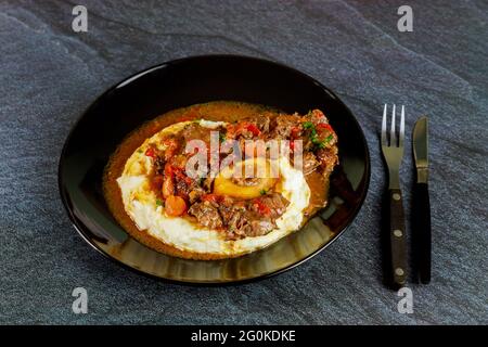 Tige de bœuf cuite avec purée de pommes de terre sur une assiette noire. Banque D'Images