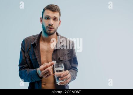 Homme malsain jeter la pilule dans le verre avec de l'eau Banque D'Images