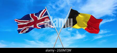 Drapeaux de la Grande-Bretagne et de la Belgique agitant dans le vent sur des mâts de drapeaux contre le ciel avec des nuages le jour ensoleillé. Symbolisant la relation, le dialogue entre deux Banque D'Images