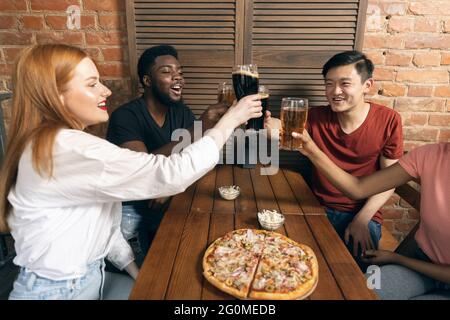 Jeunes hommes et filles, rencontre d'amis au café, pub. Concept d'amitié, d'activité de loisirs, d'émotions, Banque D'Images