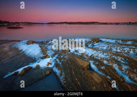 Formation de neige sur le rocher et lumière d'hiver en soirée par l'Oslofjord à Oven, Råde kommune, Østfold, Norvège, Scandinavie. Banque D'Images