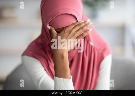 Portrait d'une femme musulmane noire désespérée dans le hijab assis à la maison Banque D'Images