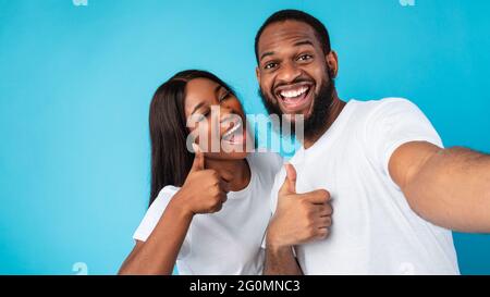 Heureux couple afro prenant le selfie en faisant des gestes et en souriant Banque D'Images