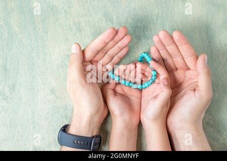 vue de dessus sur les mains d'enfant tenant des perles rosaires dans les mains de père. Fond de Kareem de Ramadan. L'homme et l'enfant musulmans tient un rosaire. Espace de copie de la mise à plat Banque D'Images