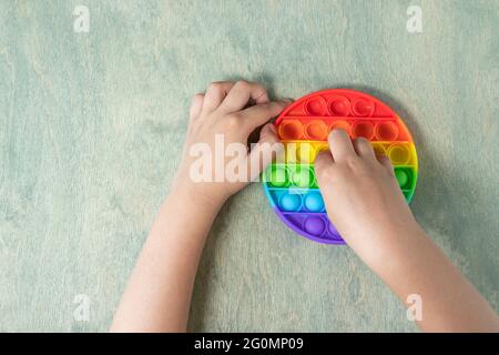 Enfant jouant avec le jouet sensoriel pop IT. Garçon appuyant sur coloré arc-en-ciel squishy doux bulles de silicone. Soulagement du stress et de l'anxiété. Jeu de violon tendance. Banque D'Images