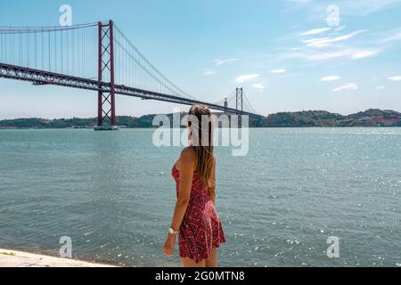 Pont du 25 avril et rivière Tage ou Tejo depuis le monument de découvertes. Bonne touriste femme à bras ouverts à la plate-forme Padrao dos Descobrimentos. Belém Banque D'Images