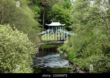 Pont de style japonais enjambant une rivière dans un parc public de campagne Banque D'Images